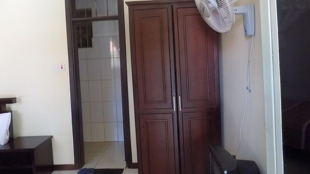 Una habitación con un armario, un ventilador y una puerta que da a otra estancia.