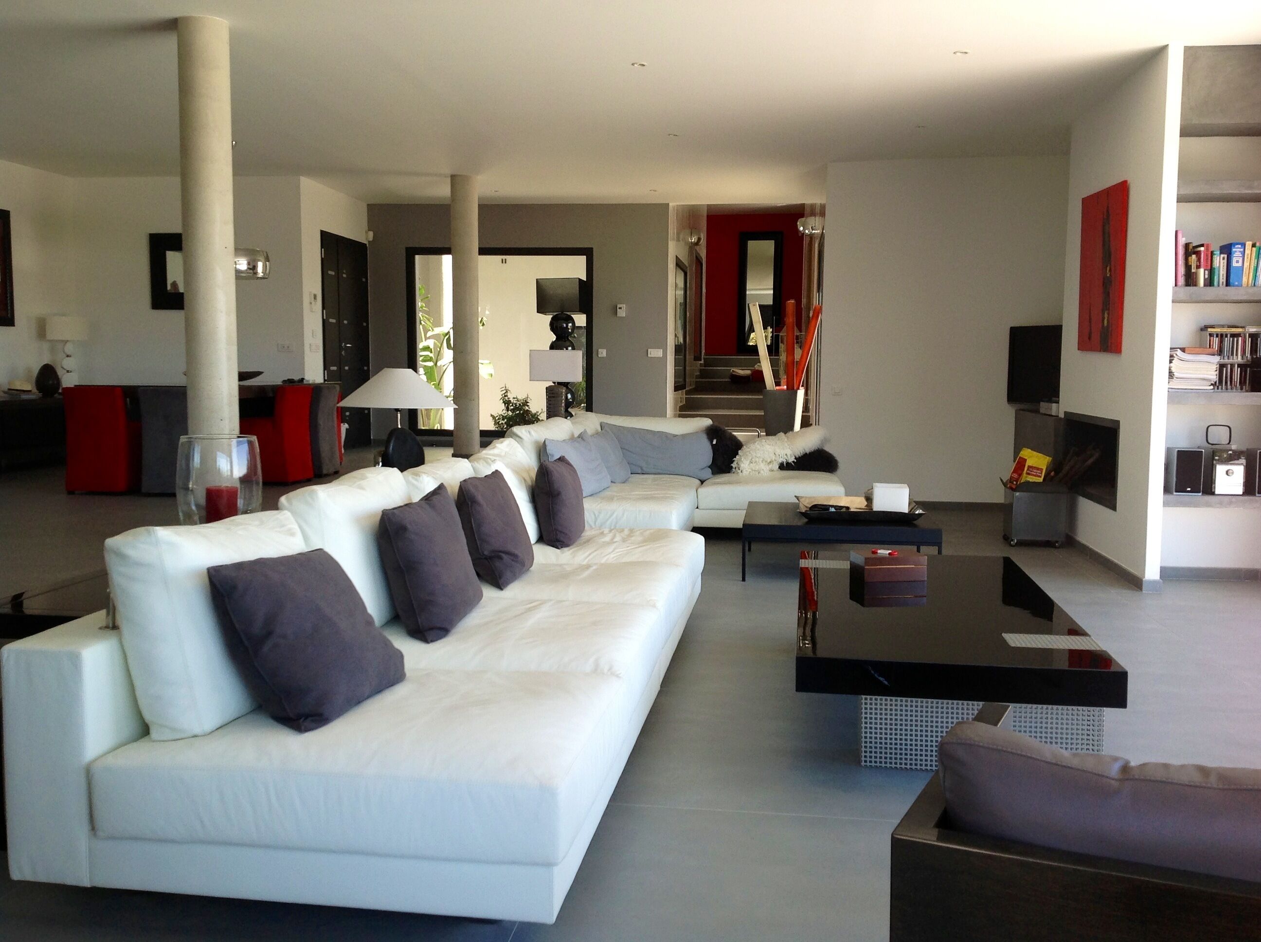 A modern living room with a white sectional sofa, a coffee table, and a bookshelf.
