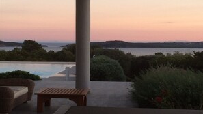 A poolside area with a view of the sea and hills during sunset. - Pinarrellu, Porto-Vecchio,calarossa,Full sea view, 7mn walk to the beach, very quiet. (sainte lucie de porto-vecchio)