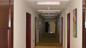 A hotel corridor with wooden doors, a patterned carpet, and recessed lighting. - Kololo Courts Hotel & Restaurant (Kampala)