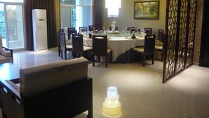 A dining area with a round table set for six, surrounded by chairs. There is a decorative light fixture in the center, and a large painting on the wall. - Kololo Courts Hotel & Restaurant (Kampala)