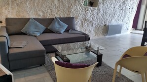 Un salon comprenant un canapé d’angle, une table basse en verre et deux fauteuils.