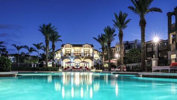 Un grand hôtel à deux étages, avec une piscine en premier plan.
