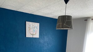 A bedroom with a bed, two bedside tables, a nightstand, a hanging lamp, and a painting on the wall. - Gite Les Marmottes Stage & stay (La Salle)