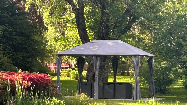 A gazebo with a roof and walls, surrounded by a pond with lily pads and greenery. - Gite Les Marmottes Stage & stay (La Salle)