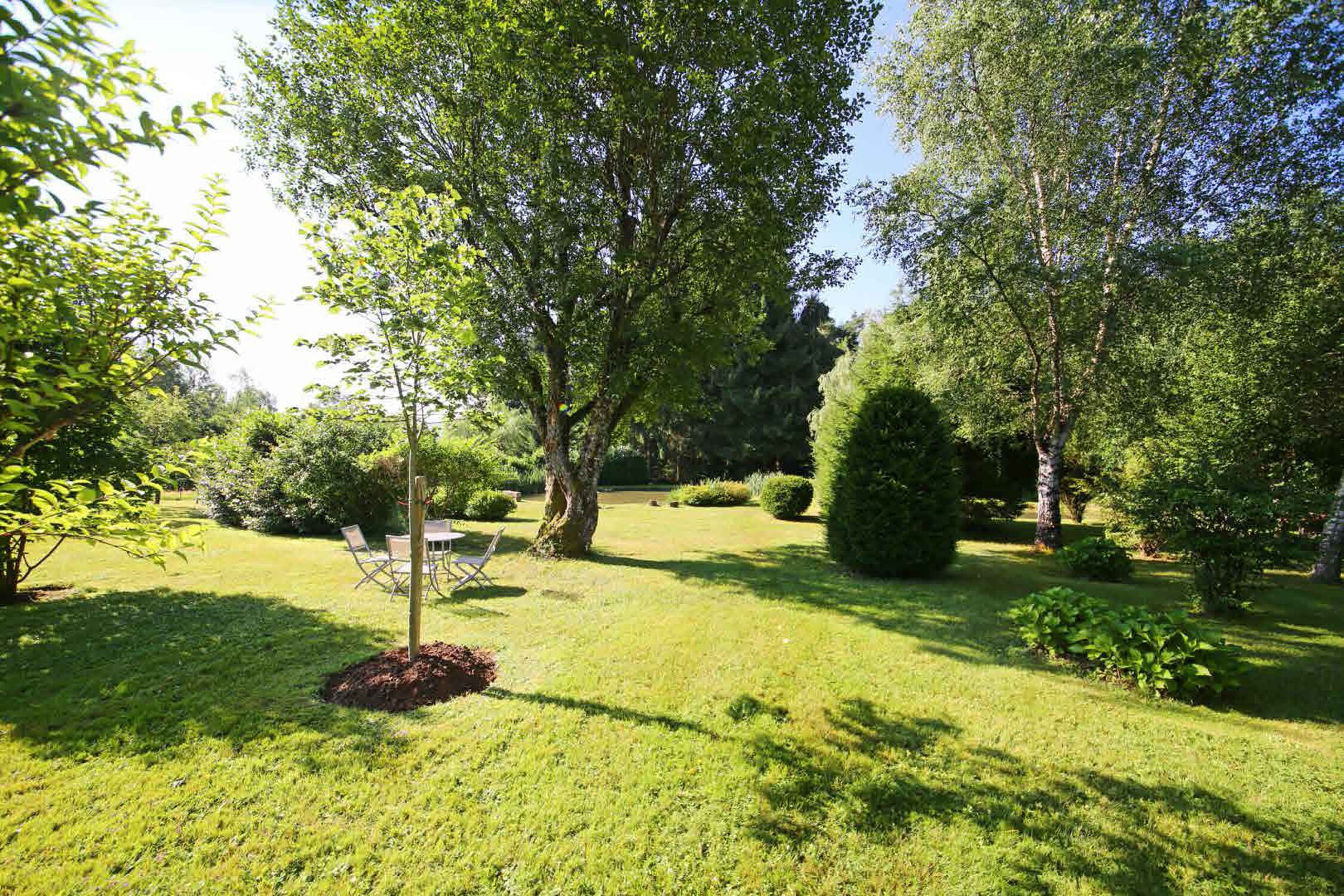 Un giardino curato con prato, un tavolo di legno e sedie.