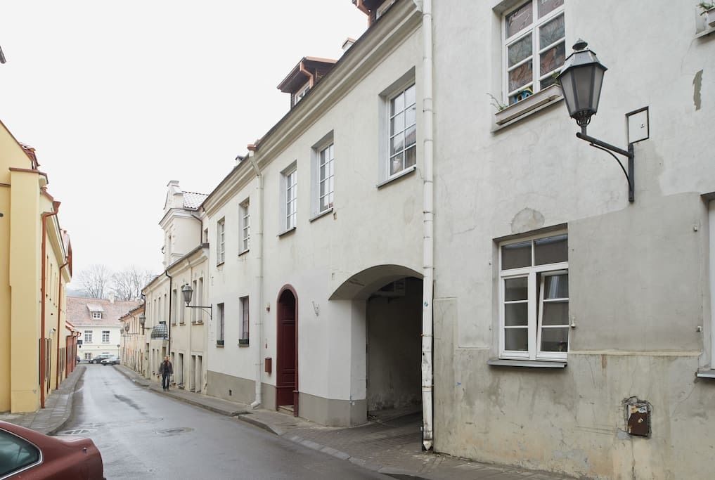 Eine enge Straße gesäumt von historischen Gebäuden, mit einer roten Tür und einem Laternenpfahl.