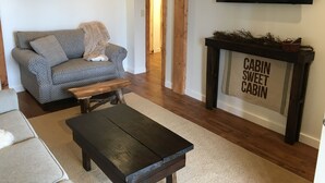 A living room with a sofa, coffee table, fireplace, and a TV mounted on the wall.