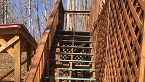 A wooden staircase with green steps and a lattice railing, surrounded by trees.