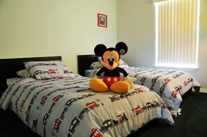 Une chambre d’hôtel avec deux lits, chacun agrémenté d’un doudou à l’effigie de Mickey Mouse posé sur le couvre-lit.