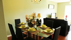 A dining area with a glass table, black chairs, yellow bowls, and a vase of flowers. - Club Cortile Resort #1 - 4 Bed 3 Baths Townhome (Kissimmee)
