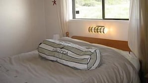 A room with a bed, a window, and a wall-mounted light fixture. - Cottage by the Sea - Ocean Front (Yachats)