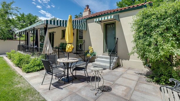 A patio area with outdoor seating, a covered seating area, and a building with a green door and striped awning. - Park Hill Holly House - A Place To Call Home  
License: 2018-BFN-0000208 (Denver)