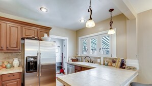 A modern kitchen with stainless steel appliances, wooden cabinets, and a large island. - Park Hill Holly House - A Place To Call Home  
License: 2018-BFN-0000208 (Denver)