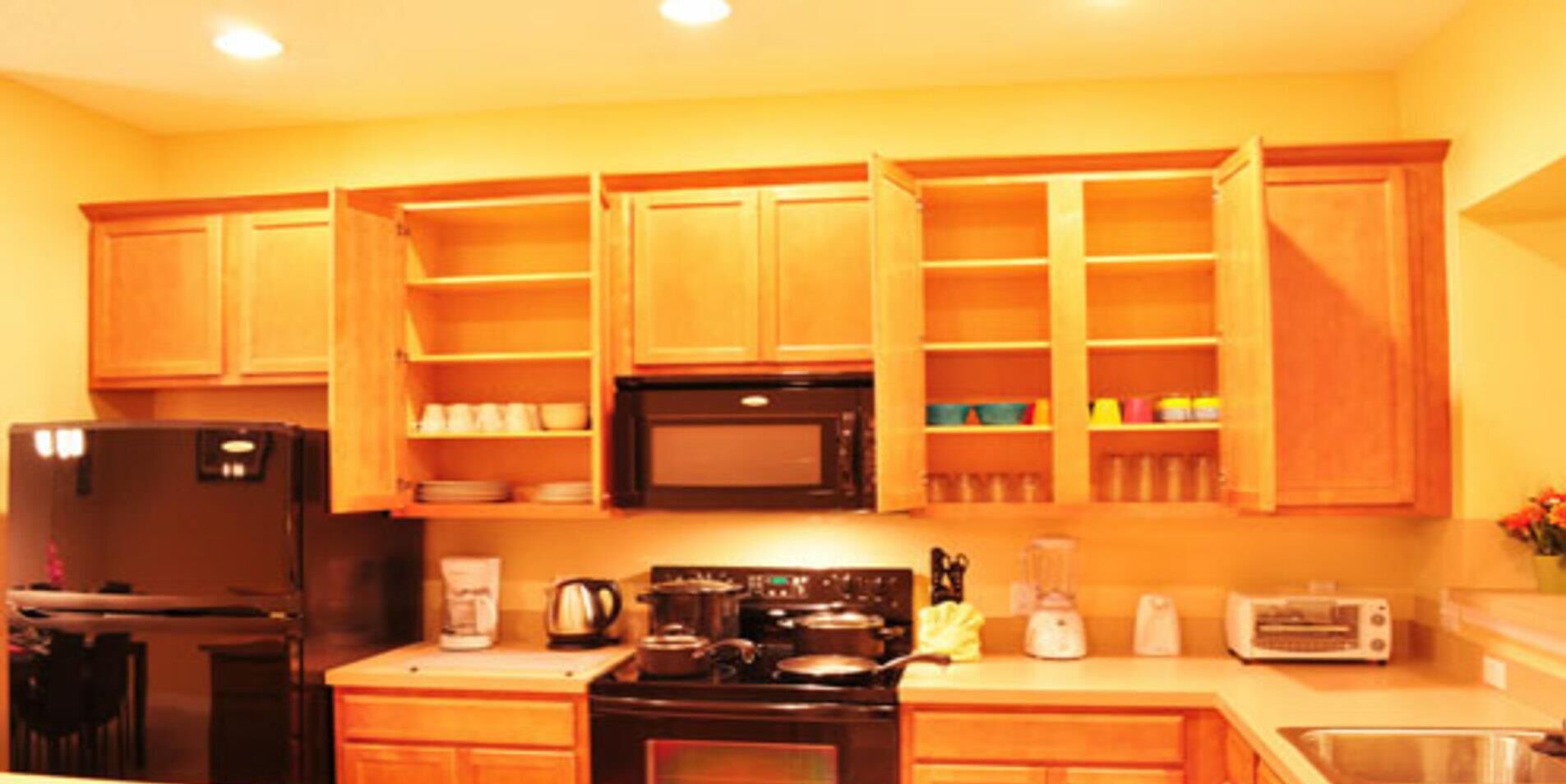 A kitchen with wooden cabinets, a refrigerator, a stove, a microwave, a toaster, and a coffee maker.