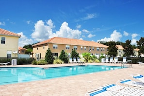 A swimming pool with lounge chairs and a building with a tiled roof in the background. - Paradise Cay #2 - 3 Bed 3 Baths Townhome (Kissimmee)