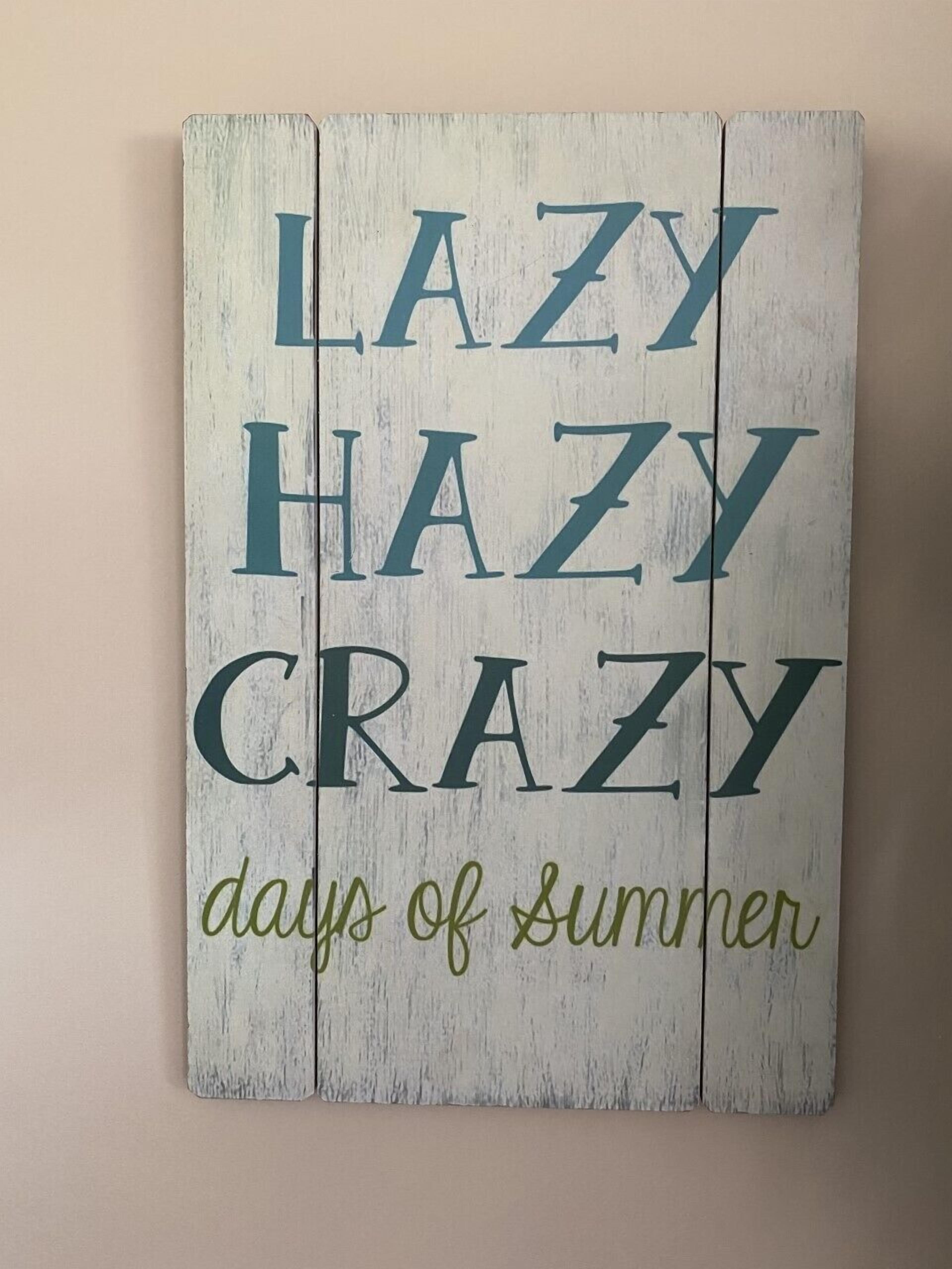 A wooden sign with the words "LAZY HAZY CRAZY days of Summer" in green and blue letters.