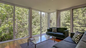 A modern living room with large windows, a glass coffee table, and a green sofa. - Neal Creek Retreat - Urban Design, Gorgeous Rural Natural Surroundings (Hood River)