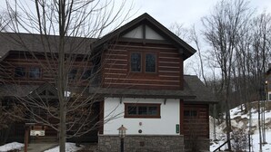 A two-story lodge with a stone foundation and wooden exterior. - Creekside Condo w/ private hot tub at Boyne!  Ski-in/Ski-out, Golf, Bike, Swim  (Boyne Falls)
