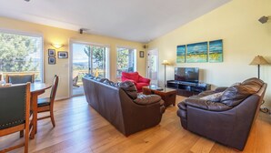 Ein Wohnzimmer mit einem Ecksofa, einem roten Sessel, einem Fernseher und Bildern an der Wand.