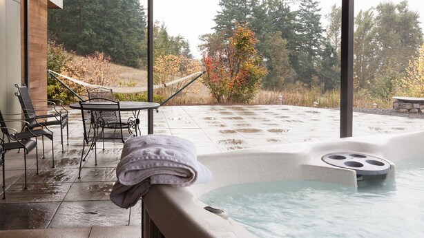 Een hottub met uitzicht op bomen en een hangmat.