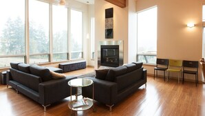 Een moderne woonkamer met een open haard, grote ramen en een zithoek.