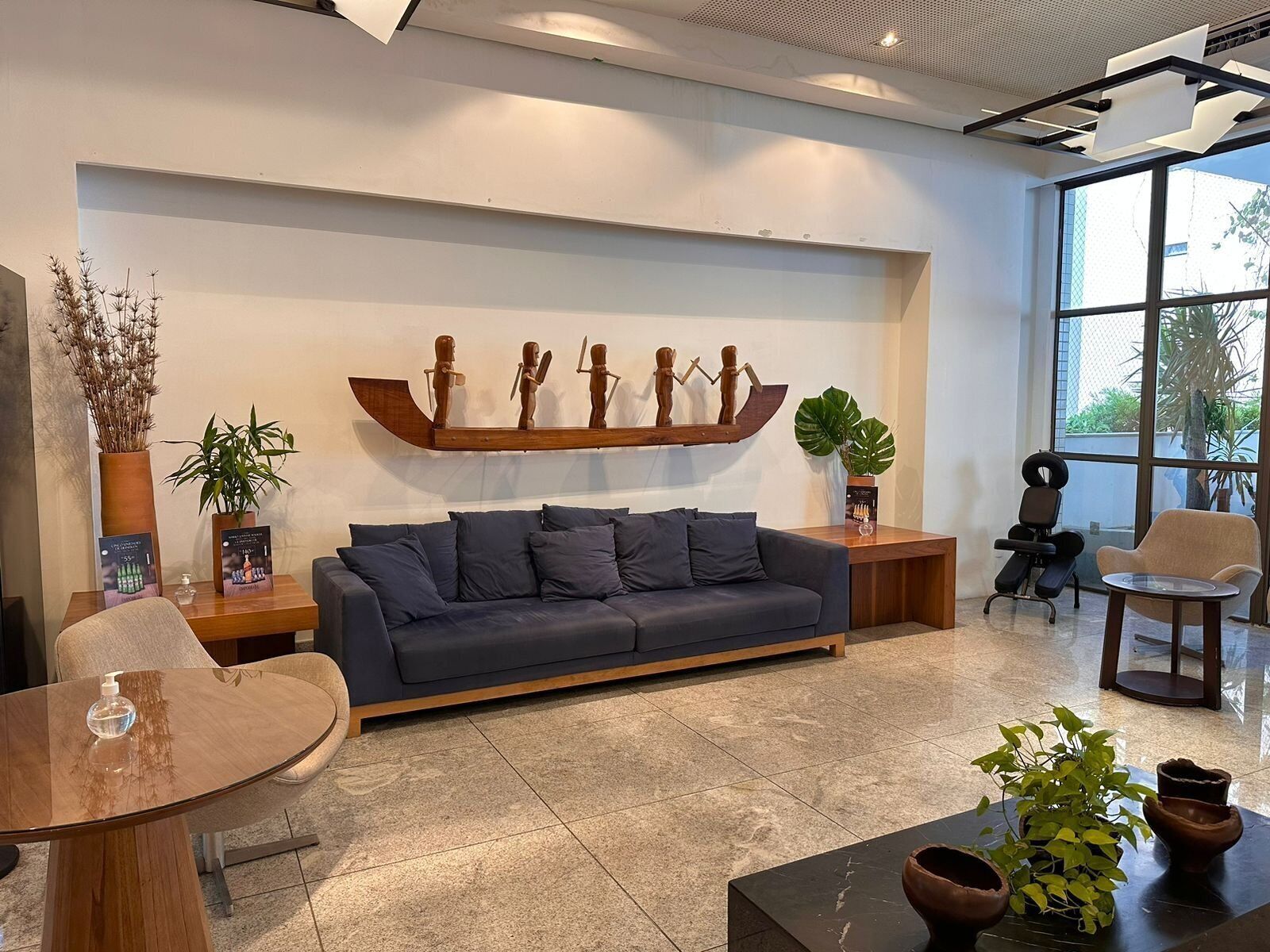 Una sala de estar moderna con un sofá gris oscuro, una mesa de centro de madera y una escultura de madera montada en la pared.