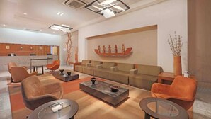 A modern living room with a sofa set, two armchairs, a coffee table, and a decorative wall piece. - HY Beach Flats (Recife)