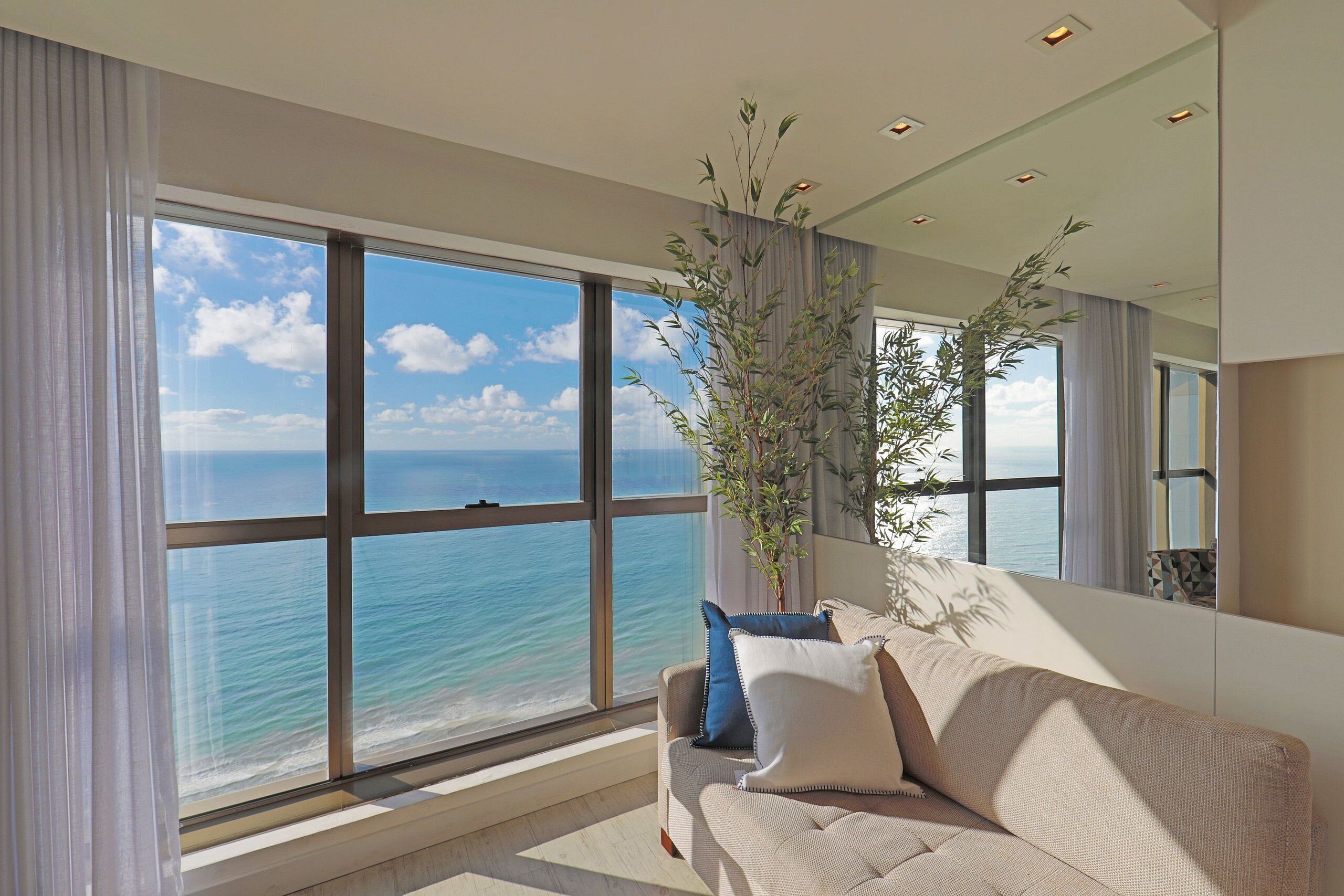 A modern living room with a large window offering a view of the ocean.