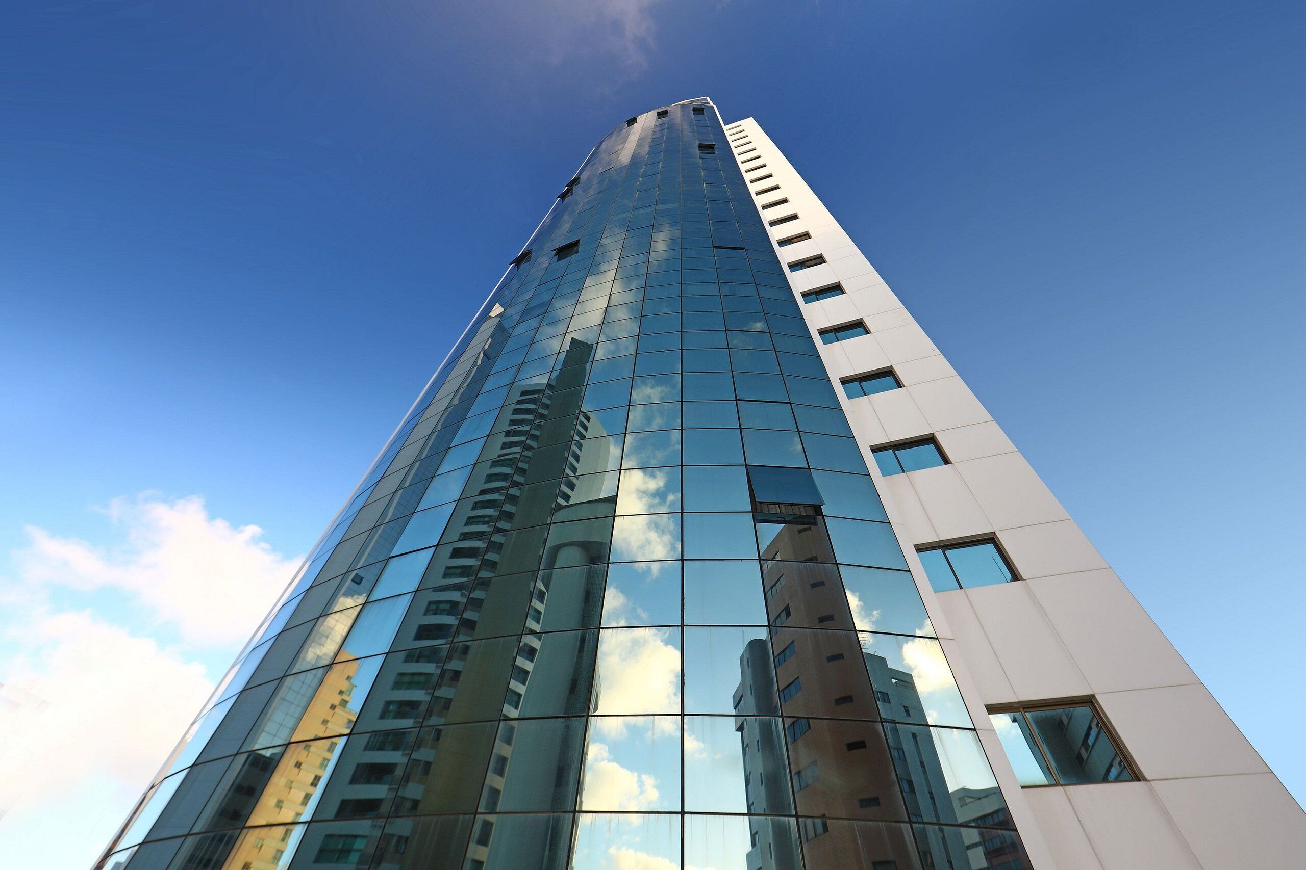 Un edificio alto y moderno con ventanas de vidrio reflectante y cielo despejado.