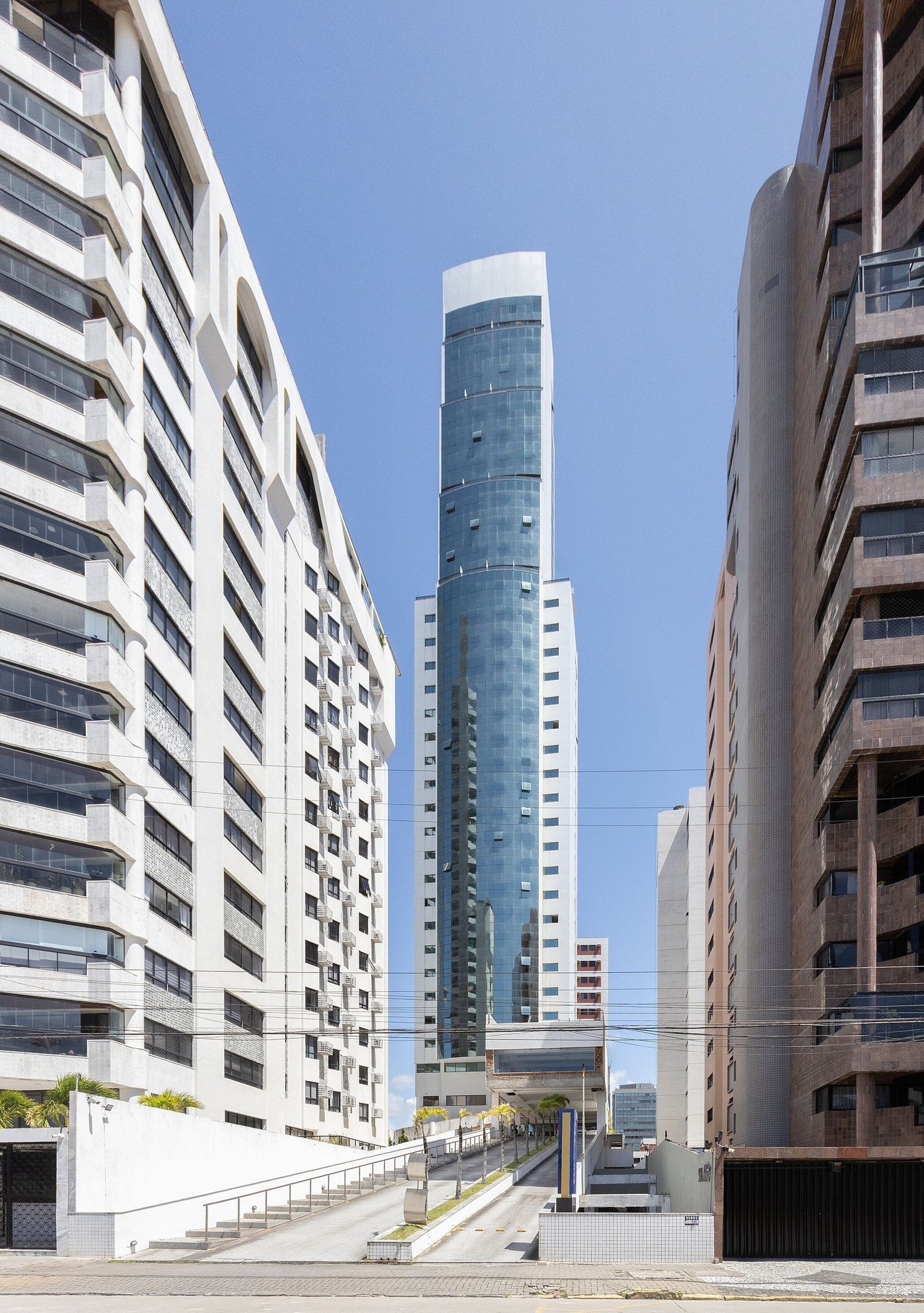 Eine moderne Stadtstraße mit Hochhäusern, blauem Himmel und einem Fußweg.