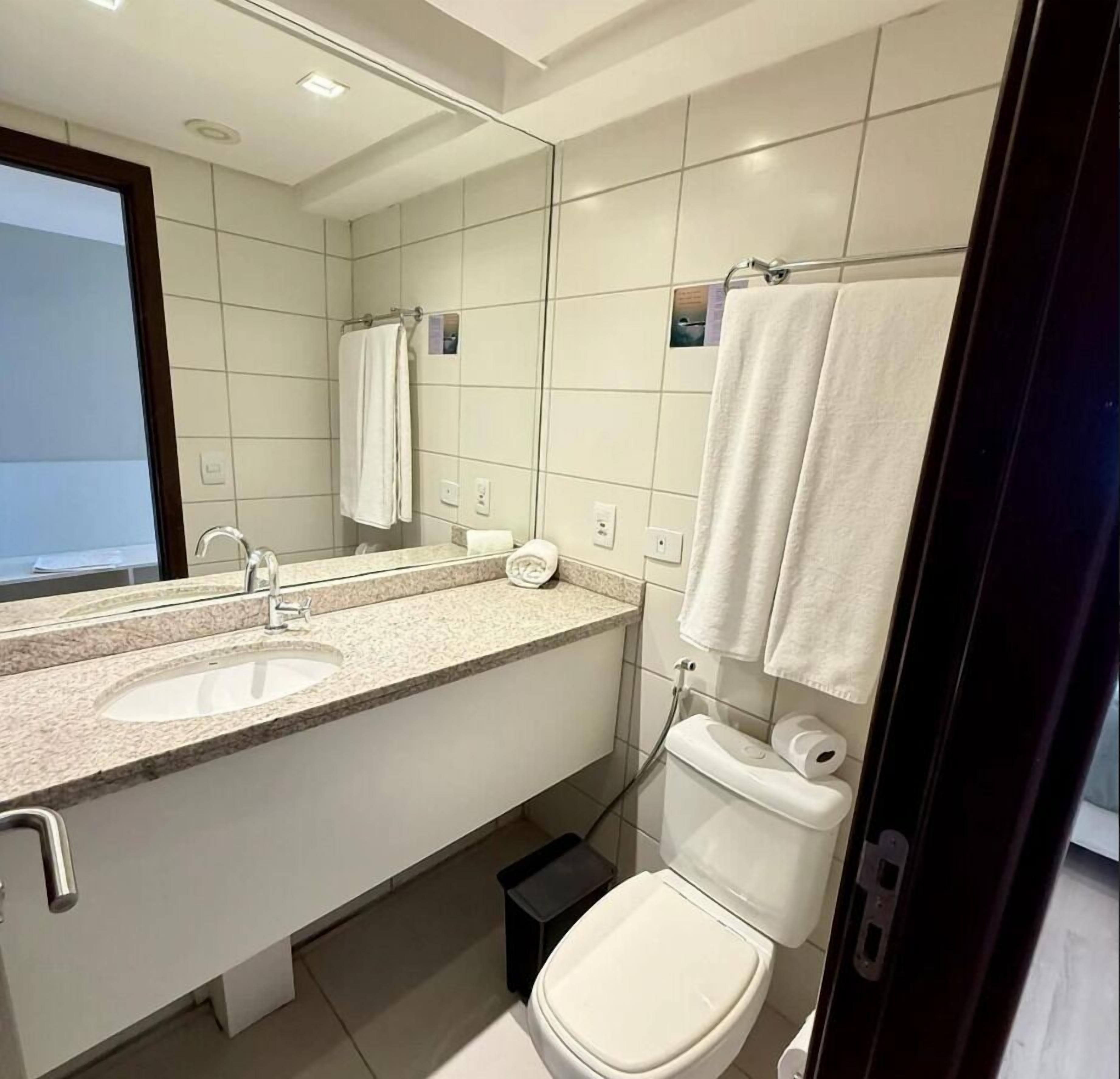 Un baño moderno con lavamanos, espejo, inodoro y toallero.