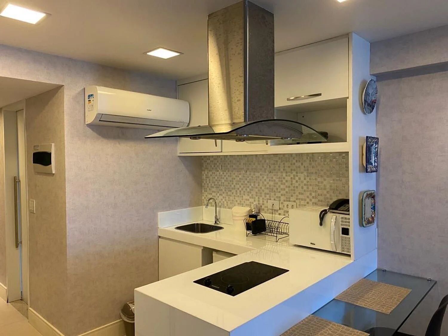 A modern kitchen with white cabinetry, a black countertop, and a built-in stove.