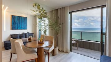 Una sala de estar moderna con una mesa redonda de madera, dos sofás y un ventanal con vista al mar.