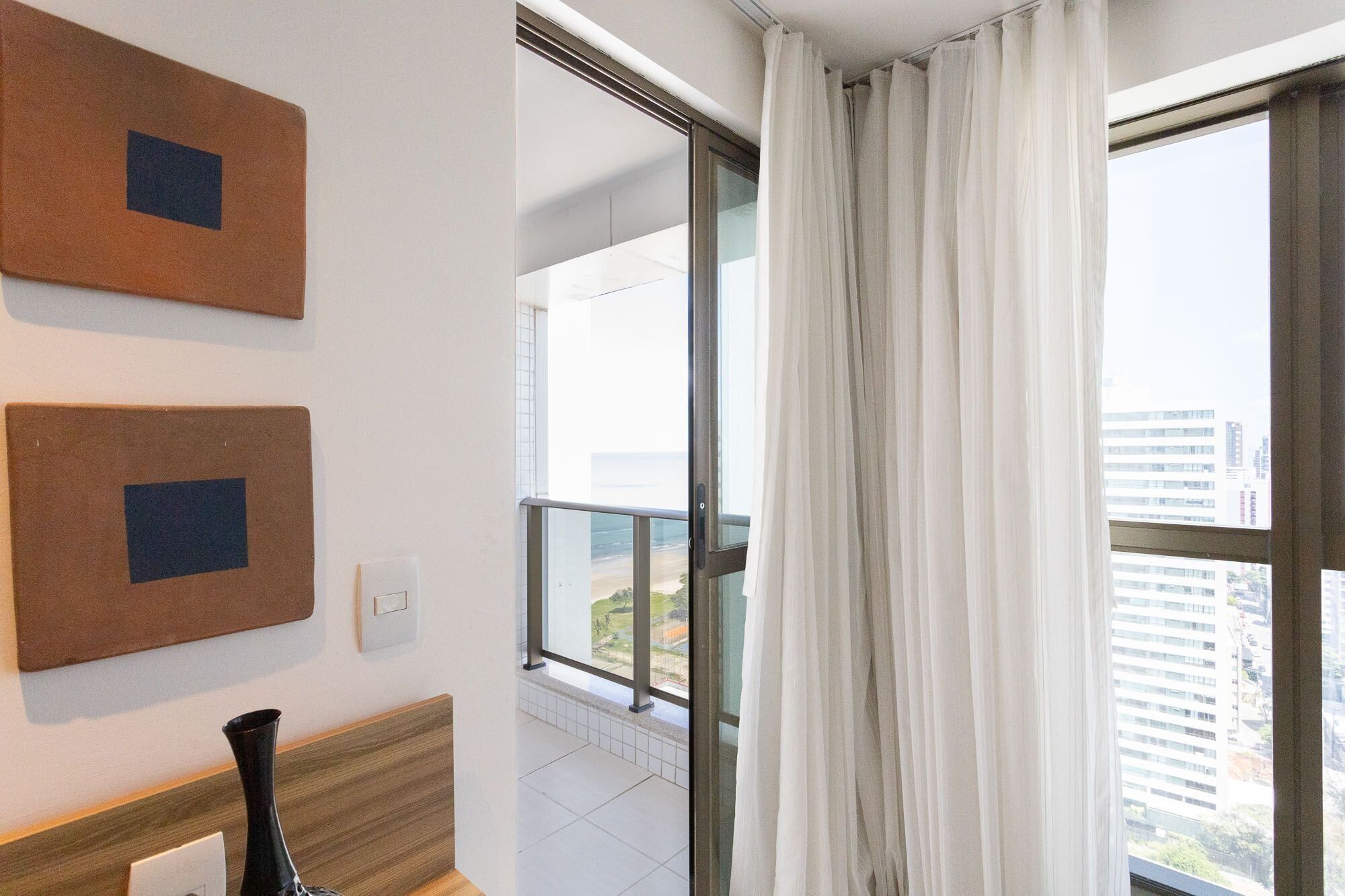 Habitación de hotel con un ventanal grande, vista panorámica de la ciudad y dos cuadros en la pared.