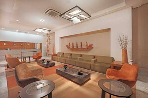 Una sala de estar moderna con un sofá, dos sillones, una mesa de centro y un adorno en la pared.