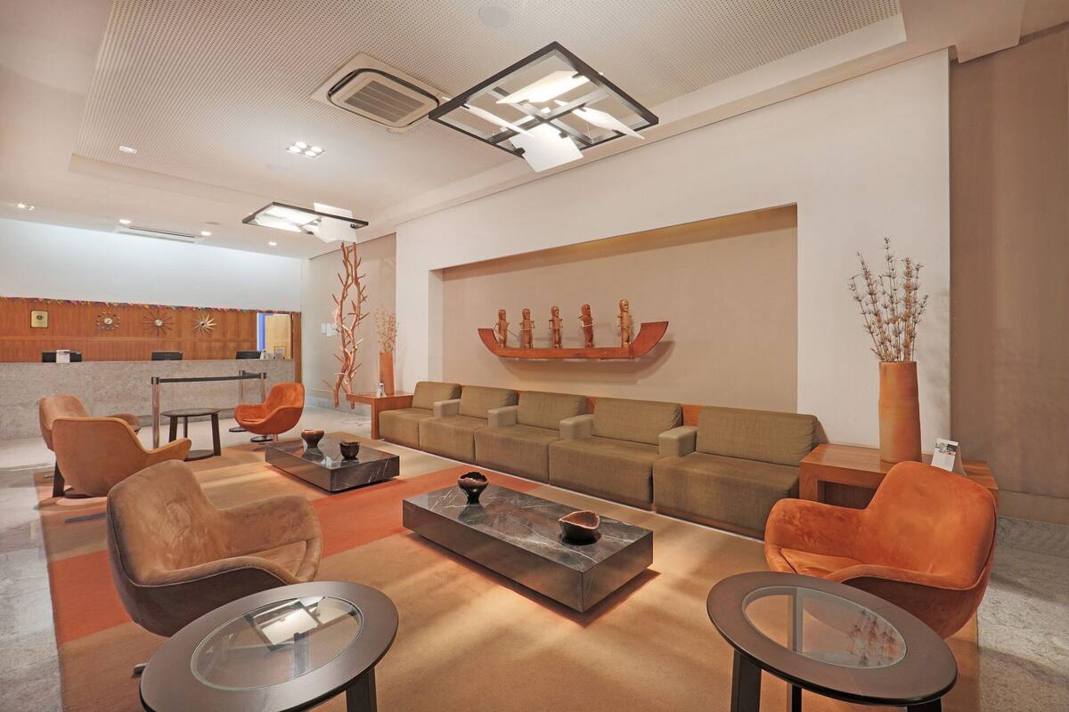 A modern hotel lobby with a seating area, a reception desk, and a decorative wall.