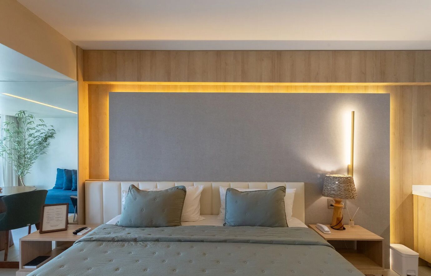 Een hotelkamer met een bed, nachtkastjes, een lamp en een plant.