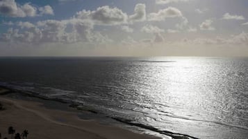 Uma praia com céu claro e luz do sol refletindo na água.