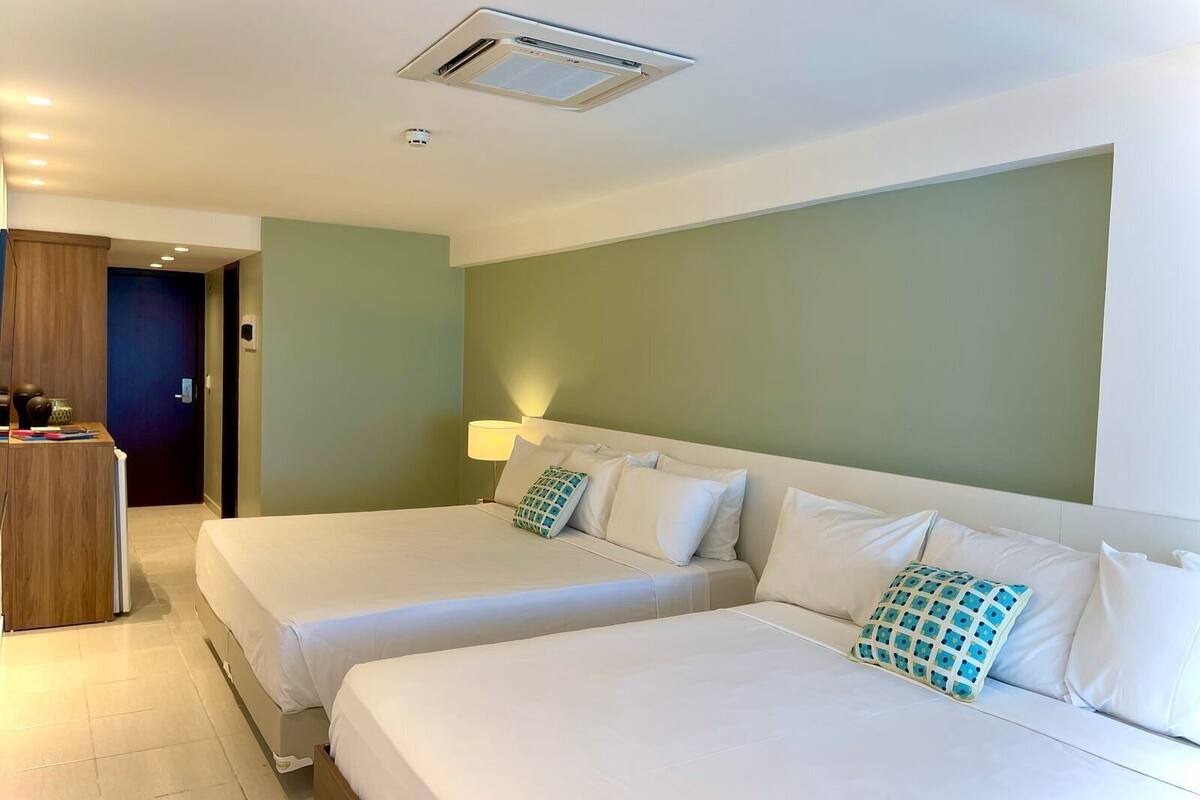A hotel room with two beds, a desk, and a door.