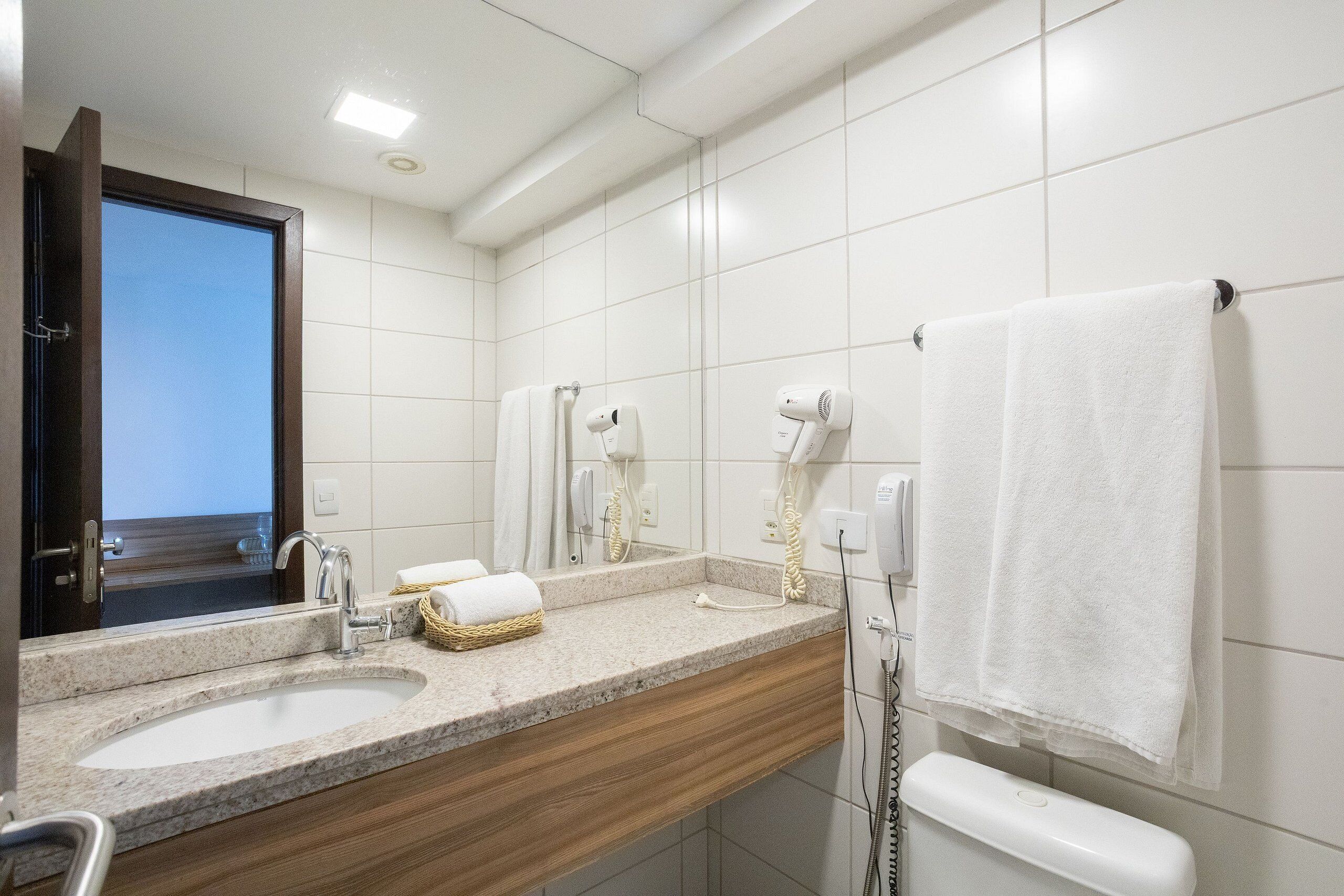 A bathroom with two sinks, a mirror, a towel rack, and a hairdryer.