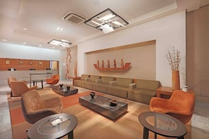 A modern living room with a sofa set, two armchairs, a coffee table, and a decorative wall piece. - HY Beach Flats (Recife)