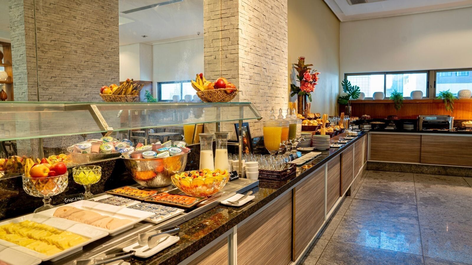 A buffet with various food items and beverages, including fruits, pastries, and juices.
