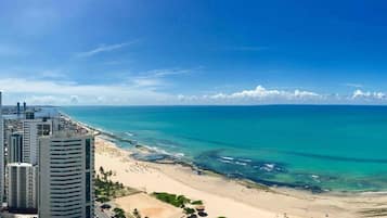 Un paisaje urbano costero con una playa, edificios altos y cielos azules despejados.