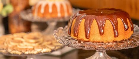 Um bolo bundt com cobertura de chocolate sobre um suporte de vidro.