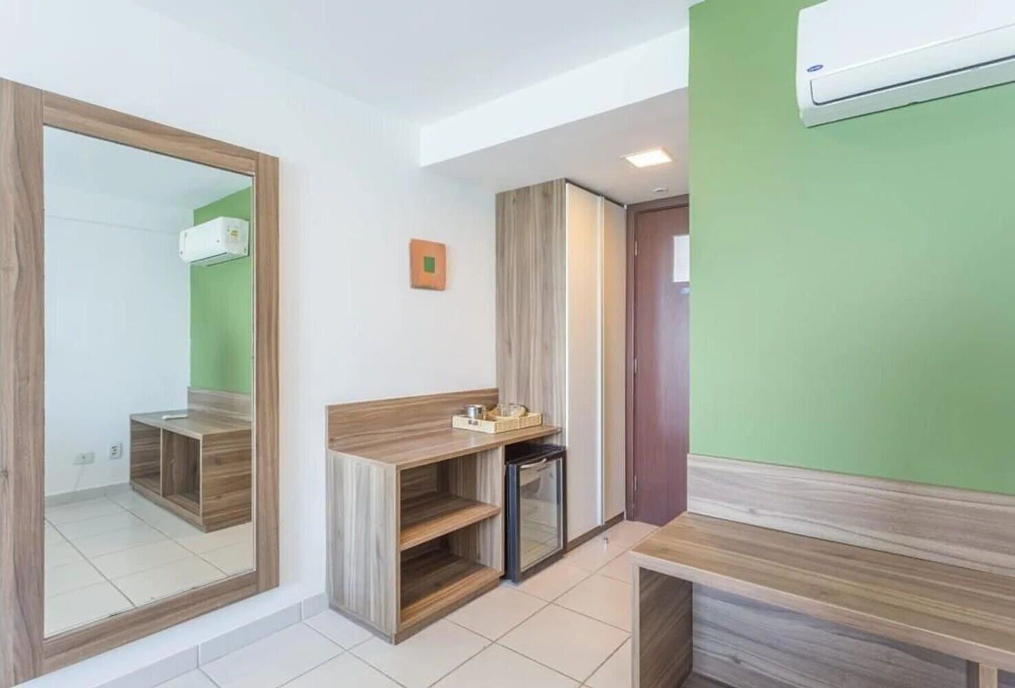 Une salle de bain moderne avec un meuble-lavabo en bois, un miroir et un mur d’accent vert.