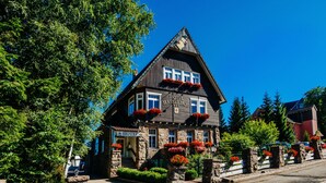 A traditional chalet-style hotel with stone walls, a steeply pitched roof, and red flower boxes. - Hotel Hasselhof Superior (Braunlage)