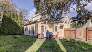 Ein zweistöckiges Haus mit überdachter Terrasse, Holzzaun und gepflegtem Rasen.