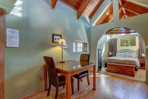 Enjoy a spacious room with a high ceiling, glass-top dining table, and a comfortable bed with a wooden headboard.