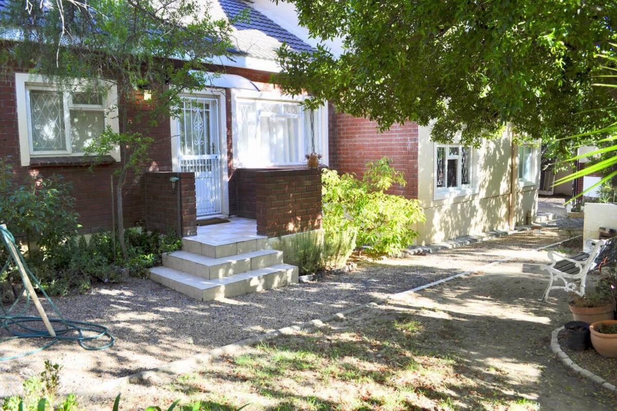 A residential house with a brick exterior, a front porch, and a garden area with steps leading to the entrance.